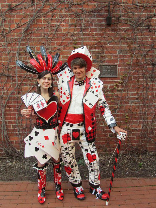 two people dressed up in costume standing next to each other on a brick floor near a wall