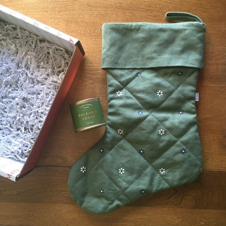 a green christmas stocking next to a can of tea on a wooden table with an open box