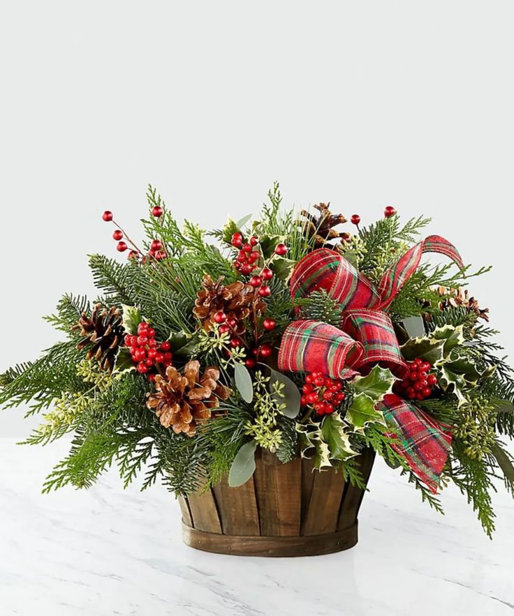 a wooden basket filled with pine cones and greenery sitting on top of a table