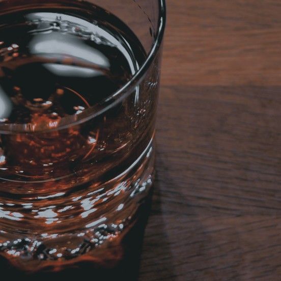 a glass filled with liquid sitting on top of a wooden table