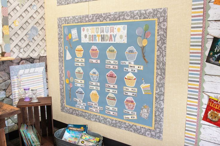 a bulletin board with cupcakes on it in front of a stone wall and wooden table