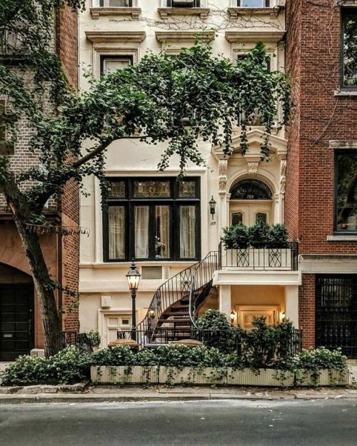 an apartment building with many windows and plants on the front, stairs leading up to the second floor