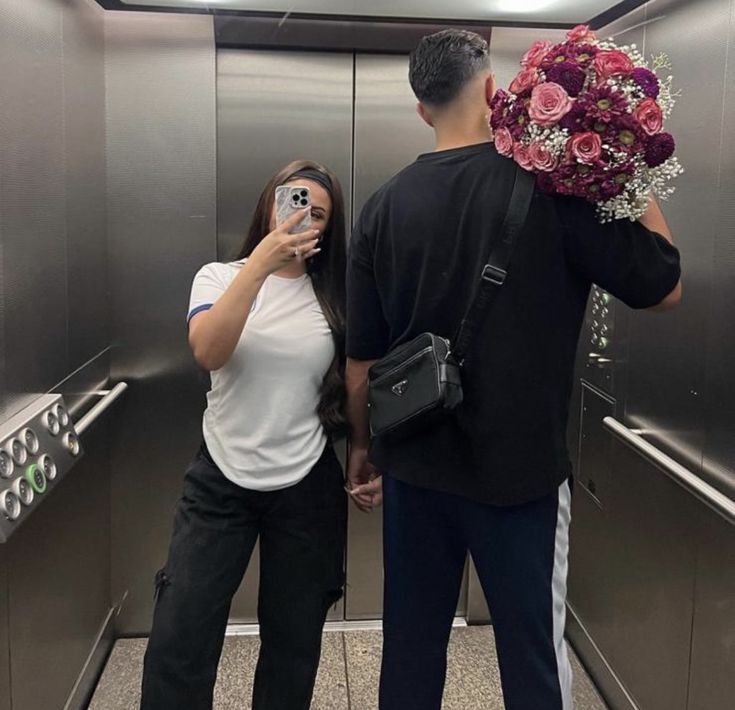 a man and woman taking pictures in an elevator