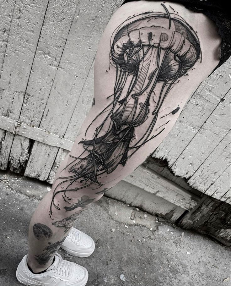 a man's leg with a black and white jellyfish tattoo on it