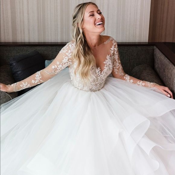 a woman in a white wedding dress sitting on a couch with her arms spread out