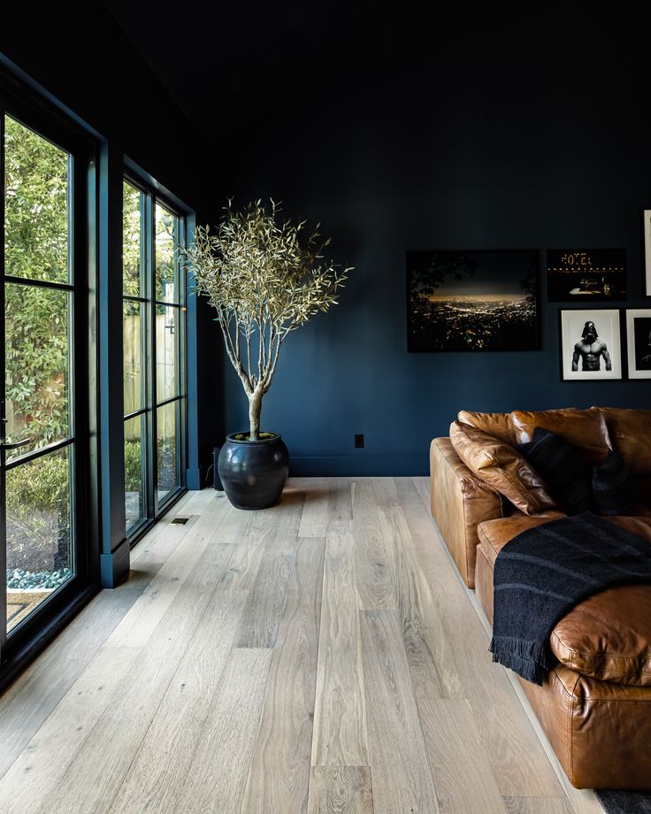 a living room with blue walls and leather couches in front of a large window