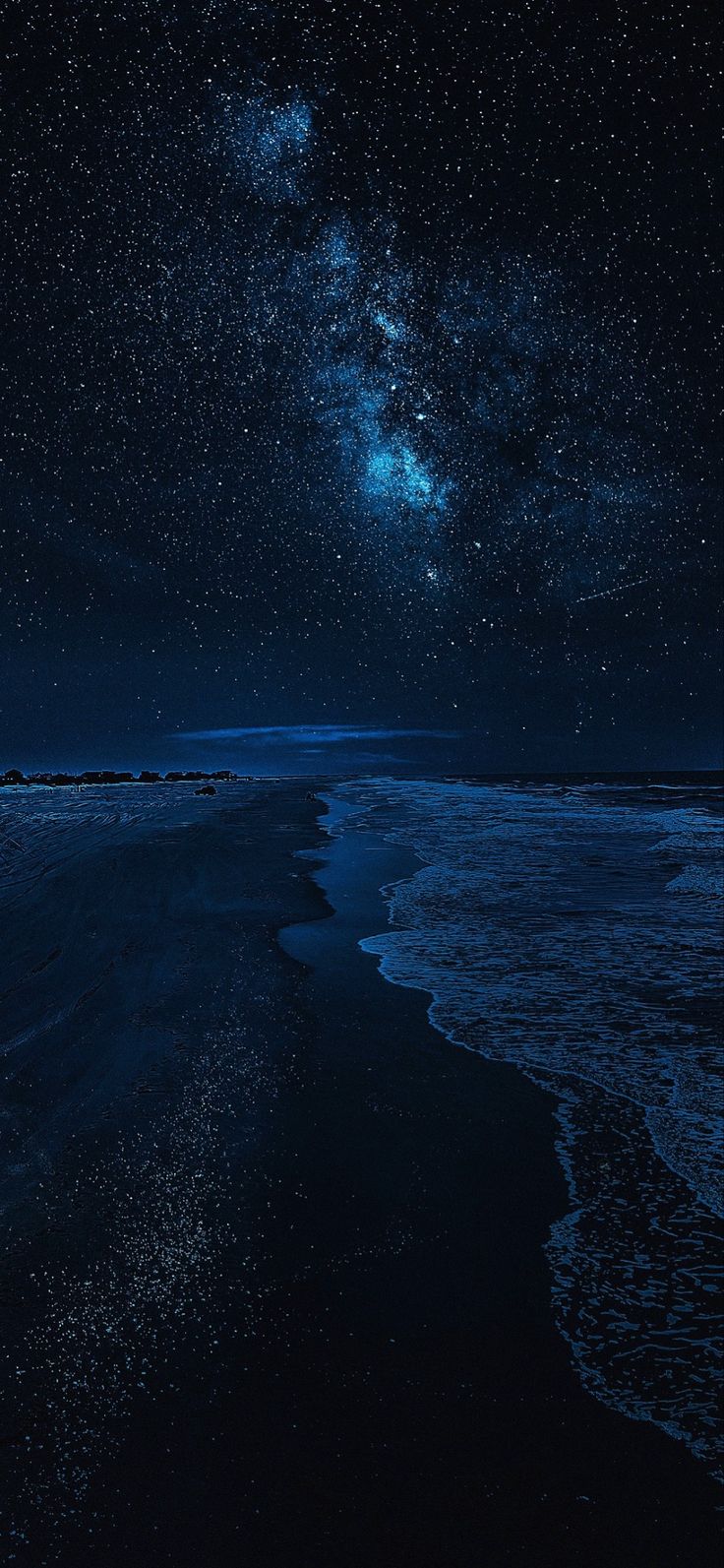 the night sky is filled with stars above the ocean and waves on the shore line