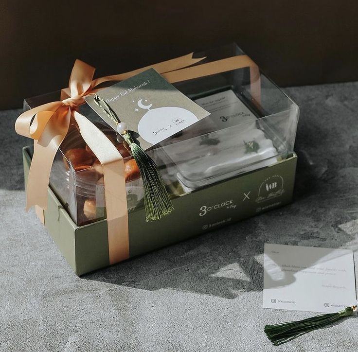 an open gift box with chocolates in it and a card on the table next to it