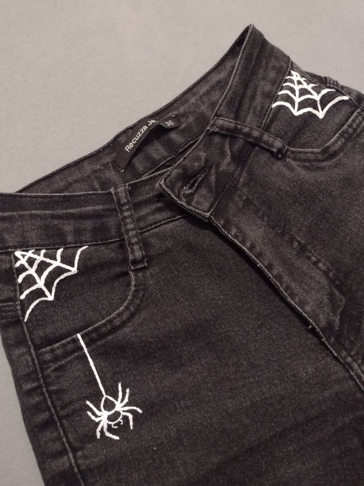 a pair of black jeans with white spider webs on them