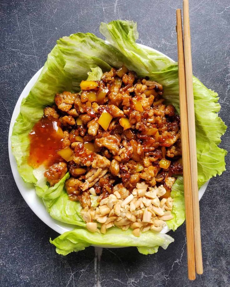 lettuce with meat and pineapples on a plate next to chopsticks