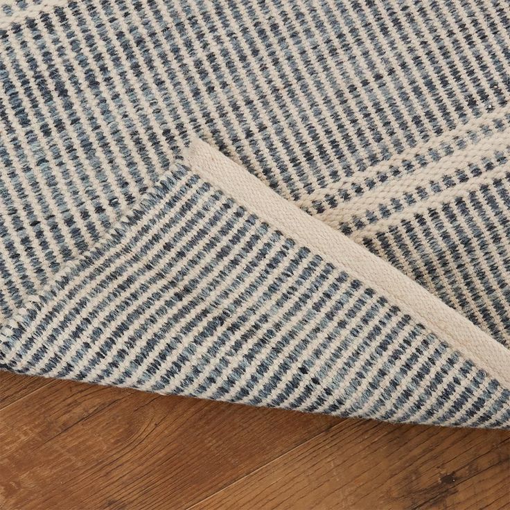 a close up view of the side of a rug on a wooden floor with a white and blue checkered pattern