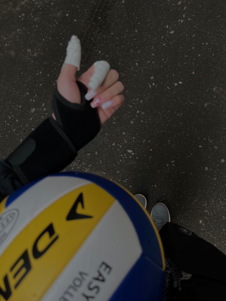 a person holding a white and blue ball in their left hand while wearing black gloves