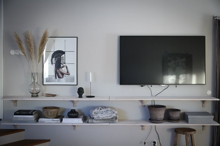 a flat screen tv sitting on top of a wooden shelf