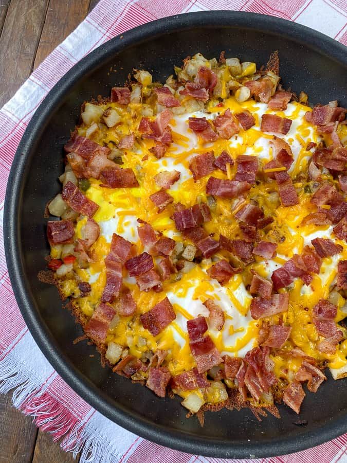 a skillet filled with bacon and eggs on top of a table