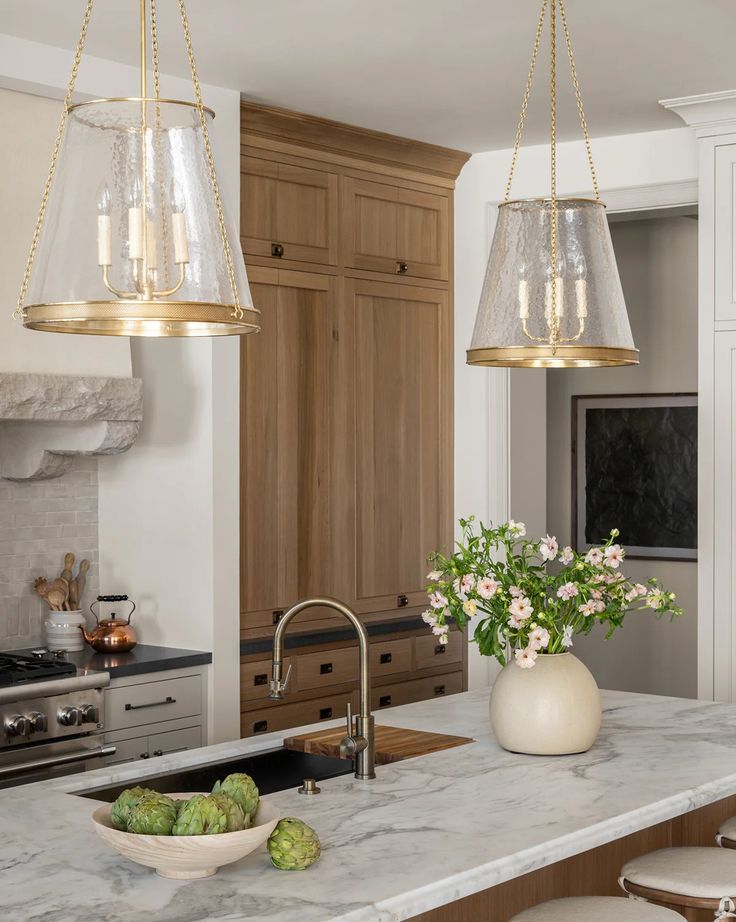 a kitchen with two hanging lights over the sink and an island in front of it