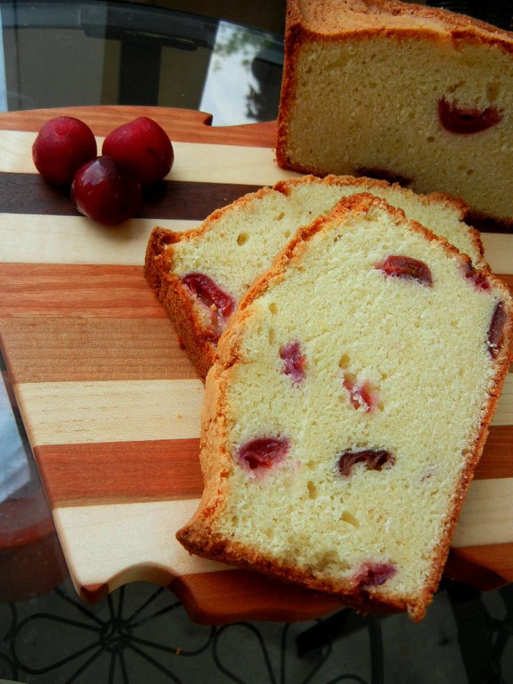 two slices of cake on a cutting board with cherries