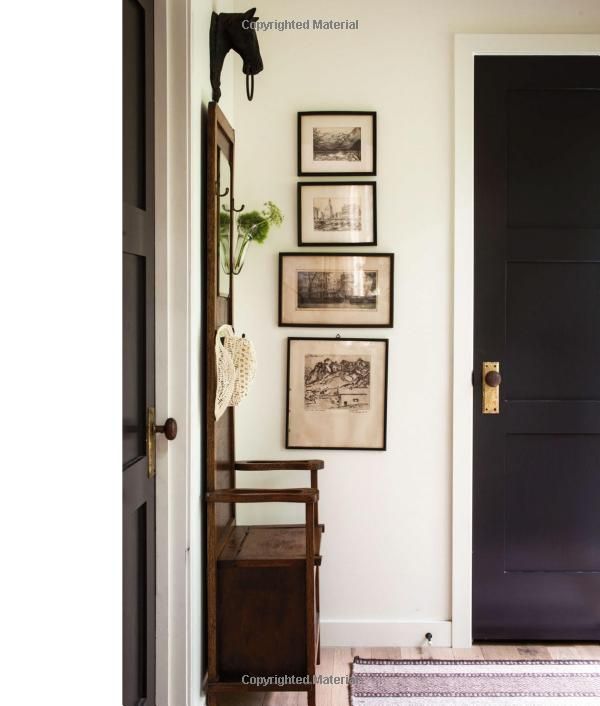 an entryway with black doors and pictures on the wall