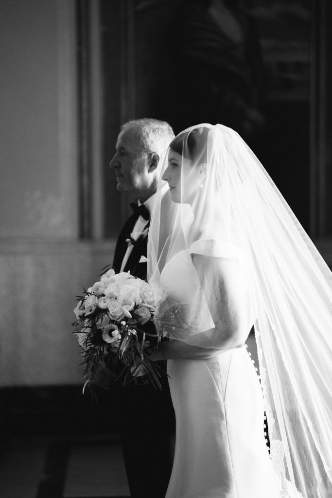 a bride and her father walking down the aisle at their wedding in black and white