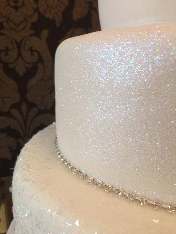 a close up of a white wedding cake with sparkles on the top and bottom