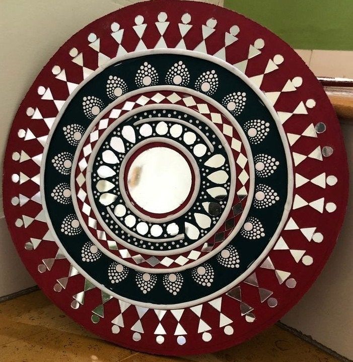 a red and black plate sitting on top of a wooden floor next to a wall