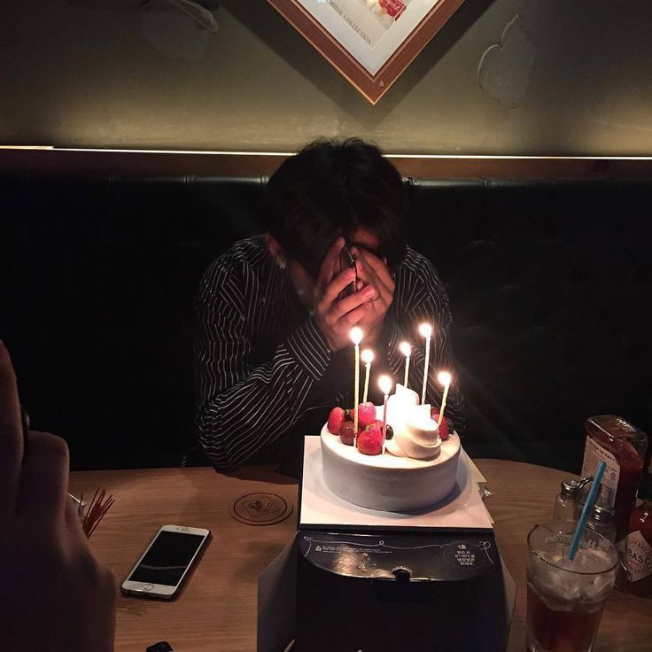 a man sitting in front of a cake with candles on it