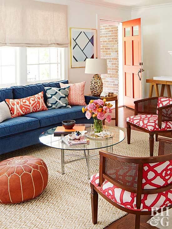 a living room with blue couches and colorful pillows on the chairs, coffee table