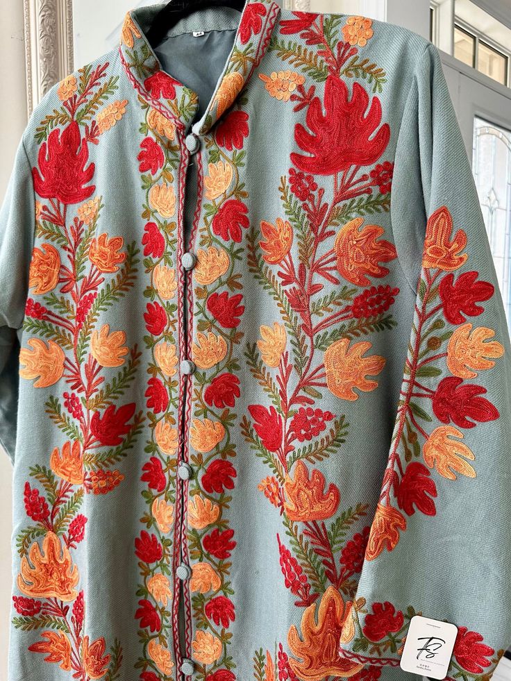 Experience the timeless elegance of our Traditional Kashmiri Floral Ari Embroidery Short Designer Jacket. Crafted with meticulous attention to detail, this versatile woolen coat features exquisite floral embroidery, reflecting the rich heritage of Kashmiri craftsmanship. With its button-up style and fully lined interior, it offers both sophistication and comfort. Elevate your winter wardrobe with this fine quality piece, blending traditional artistry with modern versatility effortlessly Conditio Spring Embroidered Multicolor Kaftan, Multicolor Floral Embroidery Nehru Jacket With Long Sleeves, Unstitched Embroidered Fabric With Embroidered Border, Nehru Jacket With Multicolor Floral Embroidery For Festivals, Traditional Cotton Nehru Jacket With Floral Embroidery, Traditional Tonal Embroidered Top For Spring, Cotton Nehru Jacket With Floral Embroidery, Multicolor Embroidered Long Sleeve Nehru Jacket, Multicolor Floral Embroidery Nehru Jacket For Festivals