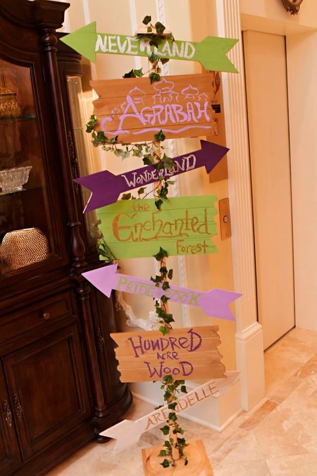 a tall wooden sign with many different signs on it's sides in front of a cabinet