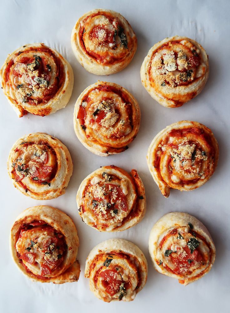 many small pastries are arranged on a white surface