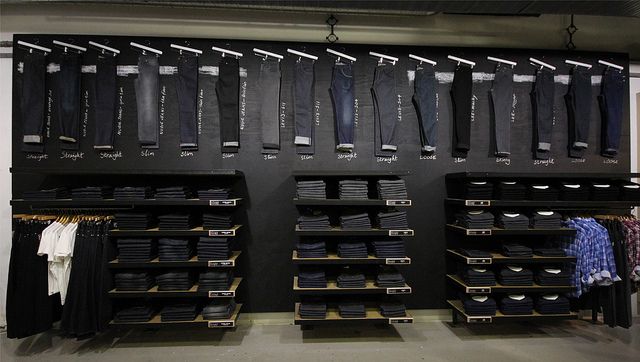 an organized closet with clothes and pants hanging on the wall in front of it's shelves