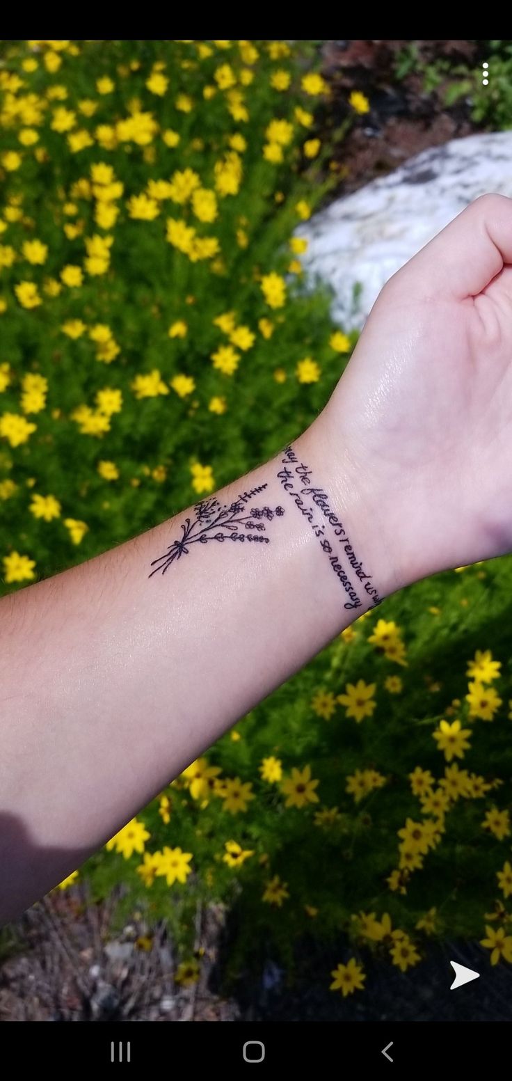 a person's arm with a tattoo on it and yellow flowers in the background