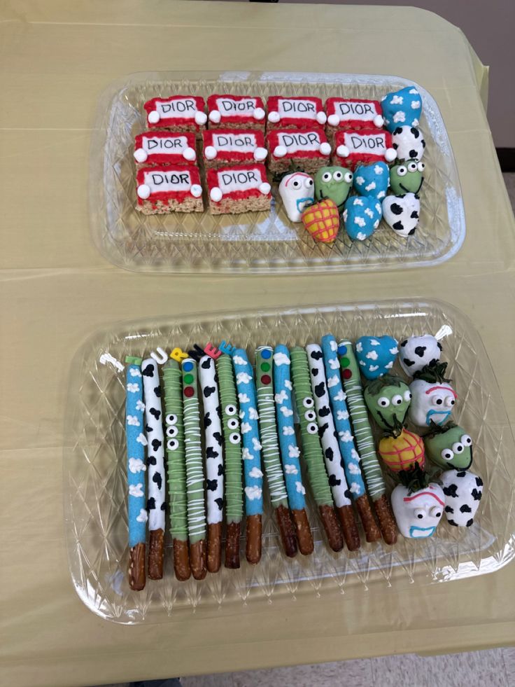 two trays filled with decorated cookies on top of a table next to each other