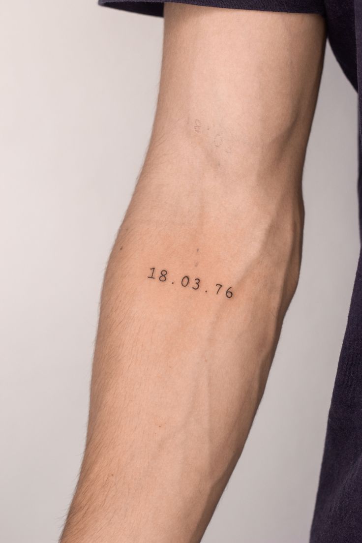 a man's arm with the date tattooed on it