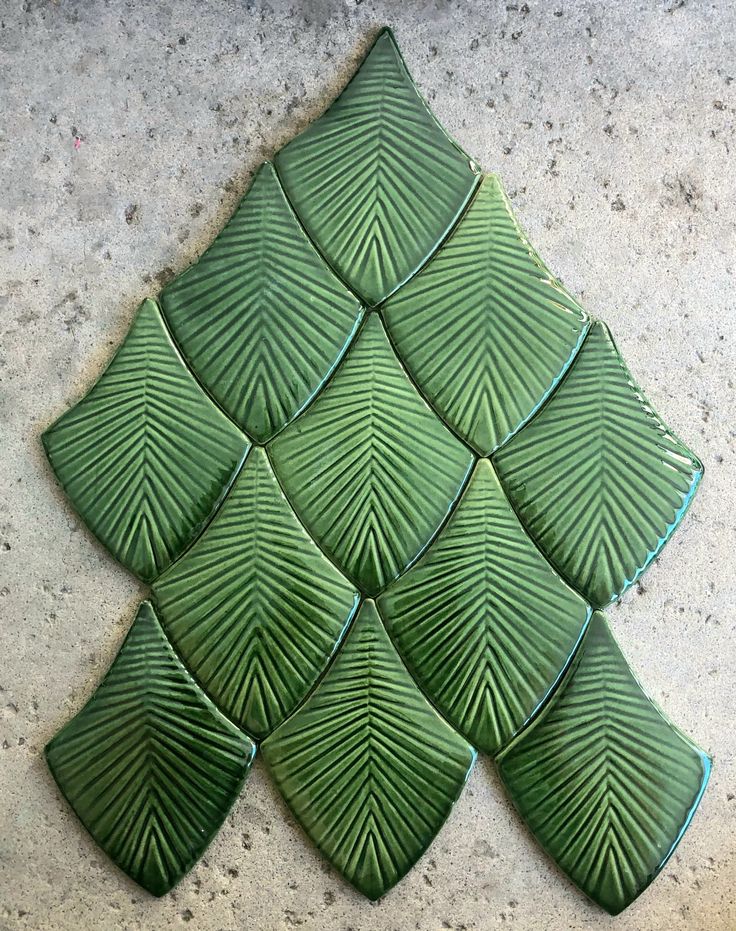 green leaves are arranged in the shape of a christmas tree on a concrete surface,