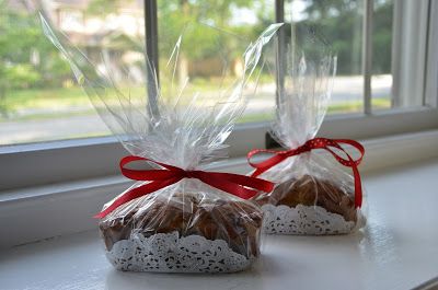 two cookies wrapped in plastic and tied with red ribbon sitting on a window sill