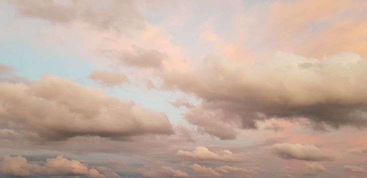 the sky is filled with clouds and there are sheep grazing in the grass on the field