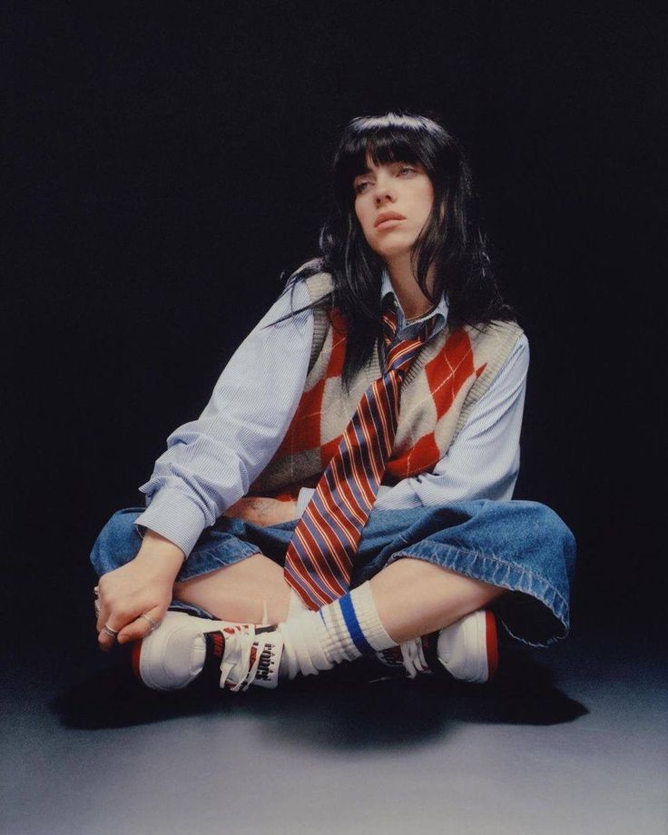 a woman sitting on the ground with her legs crossed wearing socks and a striped tie