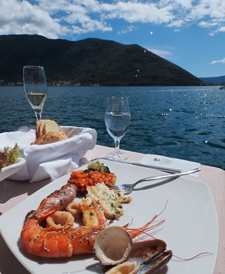 there is a plate of food on the table next to some wine glasses and water