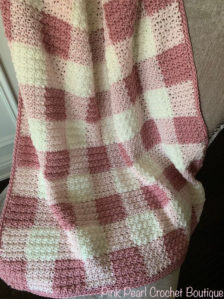 a pink and white blanket sitting on top of a couch