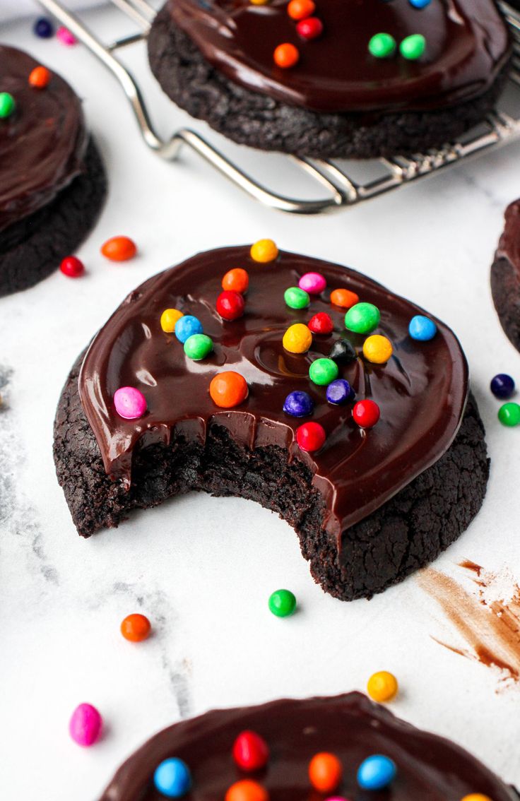 cookies with chocolate frosting and m & m candies on the top one is cut in half