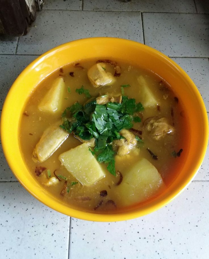 a yellow bowl filled with food on top of a tiled floor