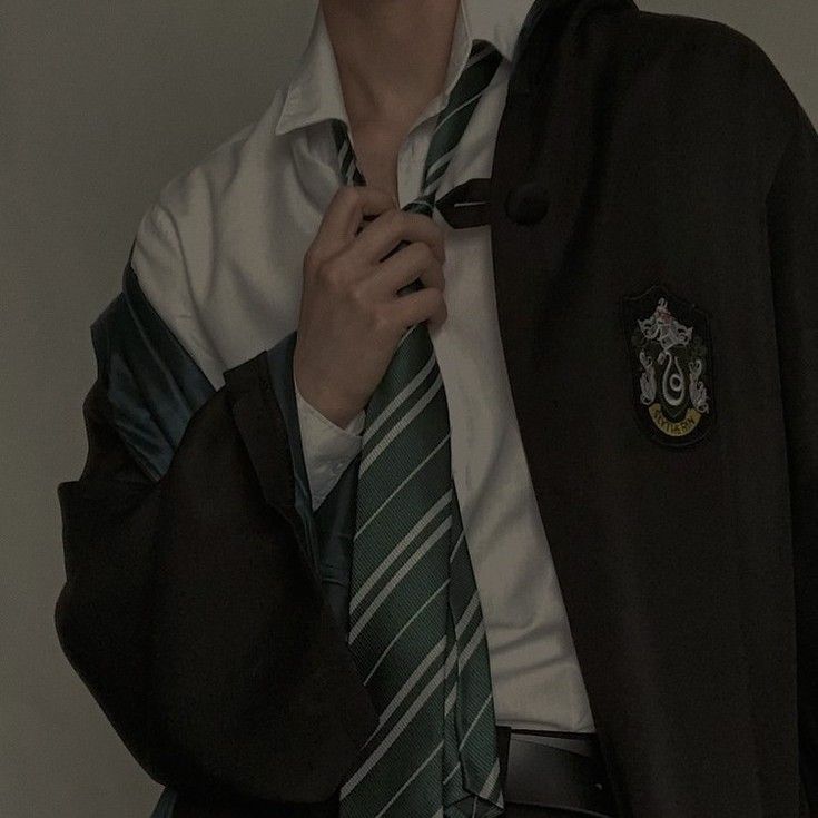 a man wearing a harry potter shirt and tie with his hands in his pockets while looking at the camera