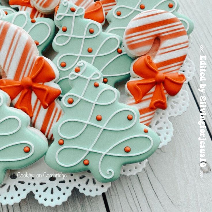 decorated cookies in the shape of christmas trees on a lace doily with bowknots