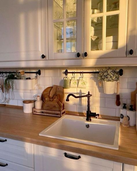 a kitchen with white cabinets and wooden counter tops, an old fashioned faucet hangs above the sink