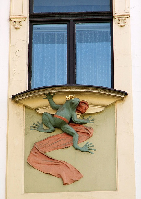 a frog on the side of a building with a window in it's center