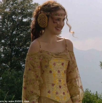 a woman in an off the shoulder dress with large earrings on her head and long hair