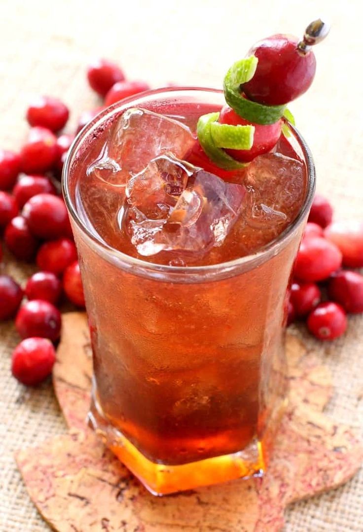 a close up of a drink in a glass on a table with cranberries