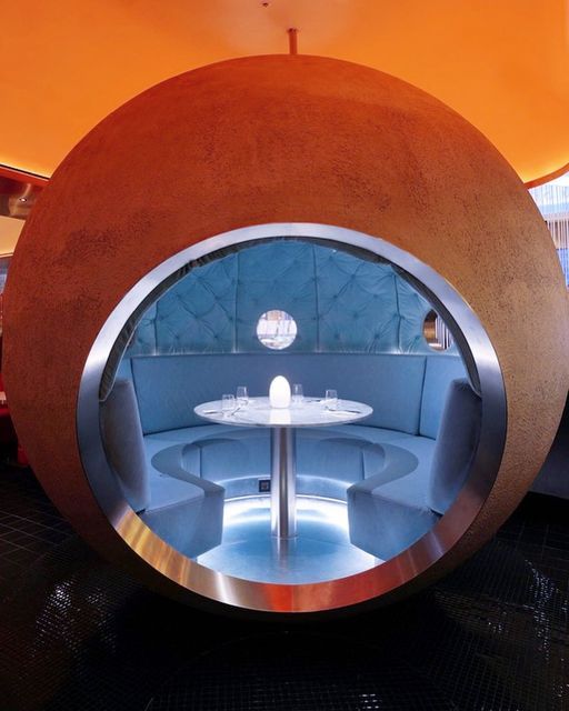 the inside of a restaurant with round tables and chairs in front of an orange wall