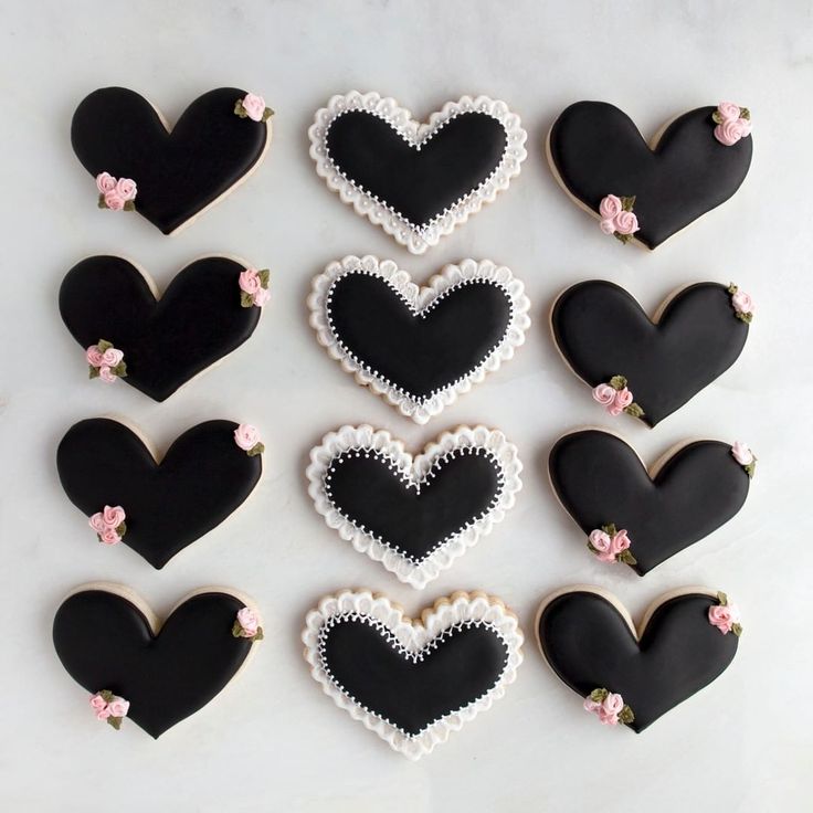 decorated cookies in the shape of hearts on a white table with pink and black flowers