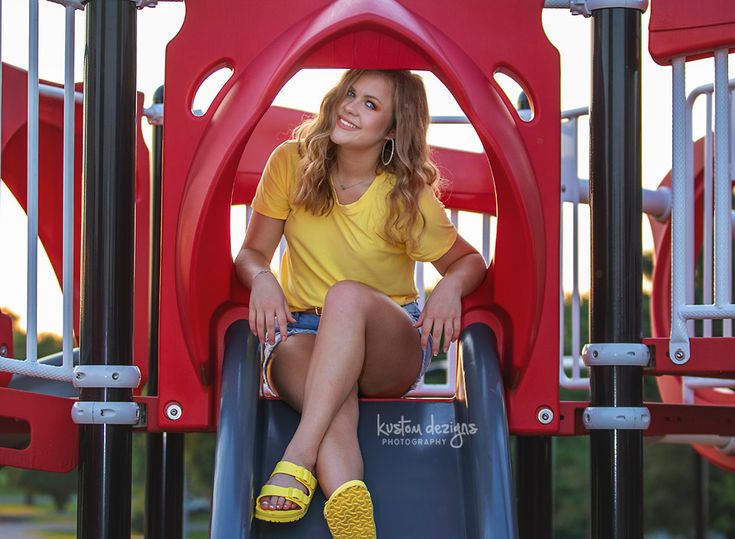 a woman sitting on top of a playground slide